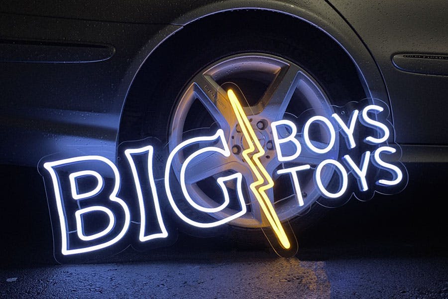 white neon sign reading big boys toys with yellow lightning bolt