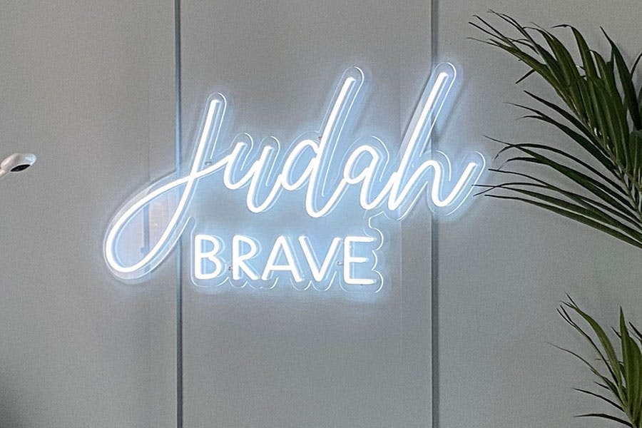 light blue neon sign reading Judah above the word brave