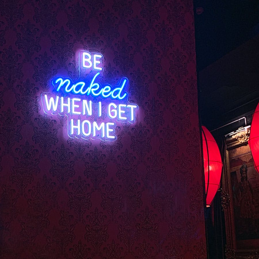 Purple and blue neon sign reading be naked when I get home