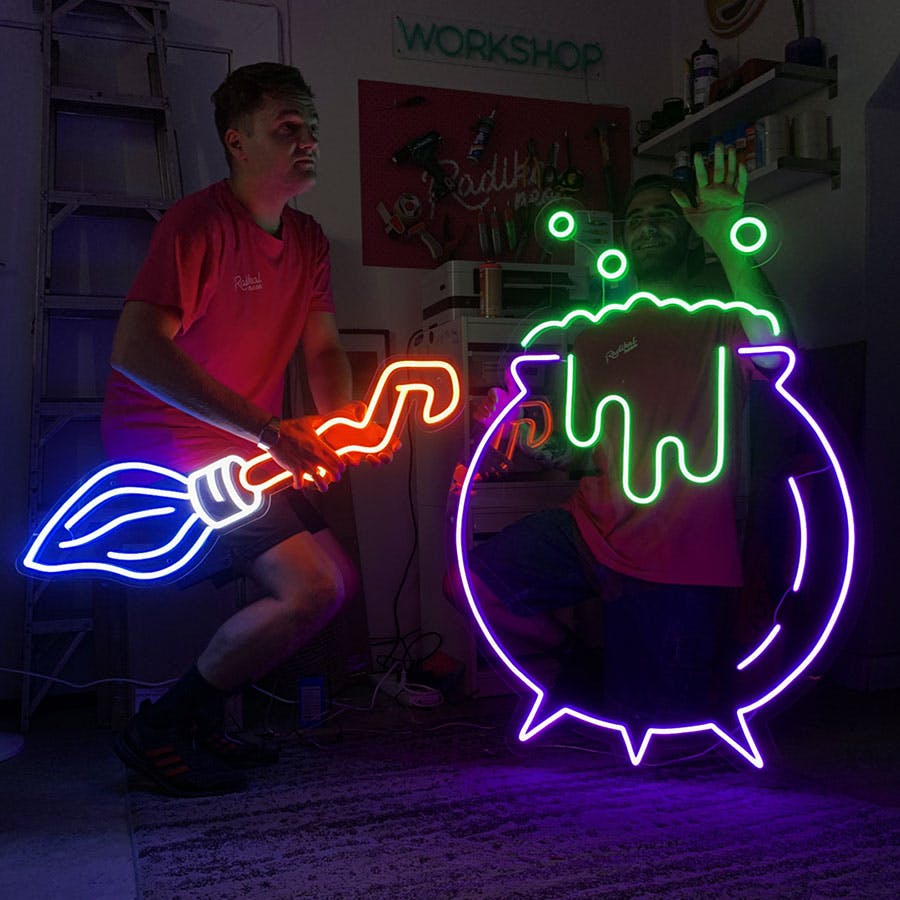 Neon signs of cauldron and broom stick