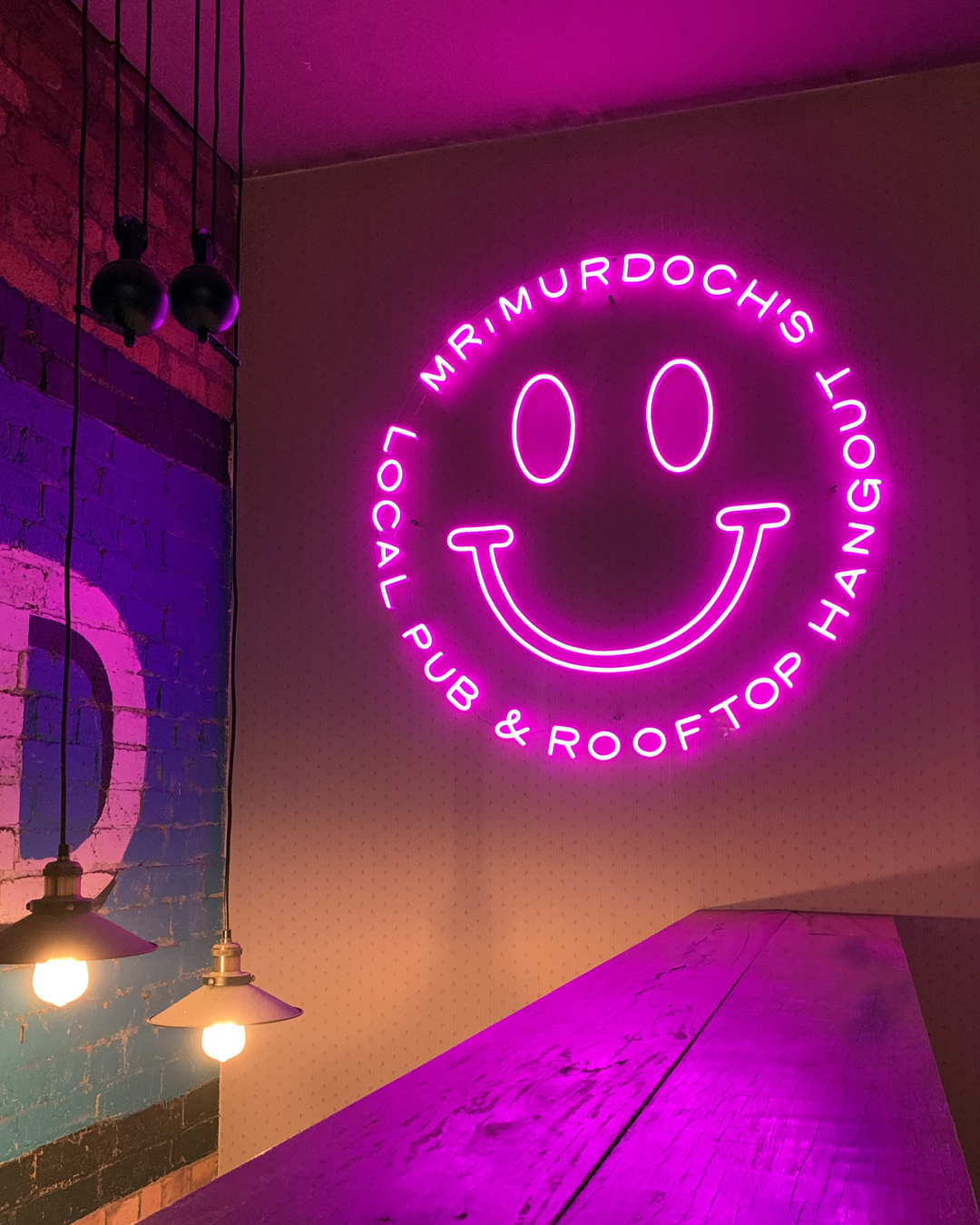 a personalized neon sign with a smiley face and text saying ‘Mr. Murdoch’s Local Pub & Rooftop