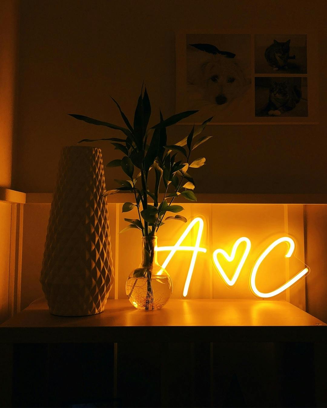 a warm yellow neon sign that says ‘A hearts C’ on a desk
